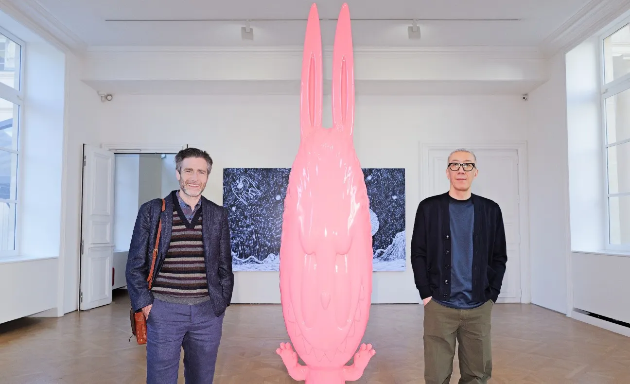 Paul King and Kasing Lung standing on either side of a large pink Labubu sculpture in a gallery